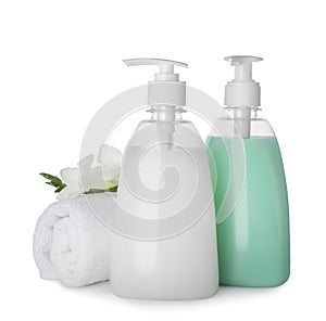 Dispensers of liquid soap, rolled towel and freesia flowers on white background