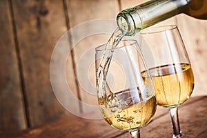 Dispensing golden white wine into two wineglasses photo