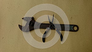 Display from above an old adjustable wrench and a small wire cutter with a brown background