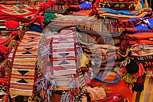 Display with assortment of bright red orient rugs with traditional ornamental patterns in middle eastern bazaar.