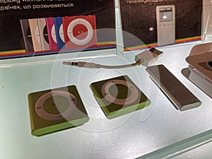 Display case of three Apple iPod models in a museum, arranged chronologically Topmost sleek black and white early generation model