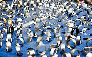 Display with different designs of handmade silver rings on blue