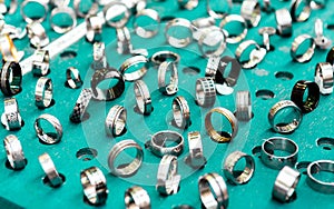Display with different designs of handmade silver rings on green