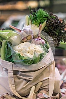 Display of fresh ripe organic broccoli, salad and greens in cotton bag at the weekend farmer`s market