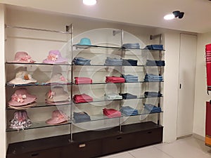 Display of ladies hats, folded tops and denims on glass shelf