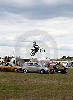 display motocross motorbike jumping over a line of vehicles