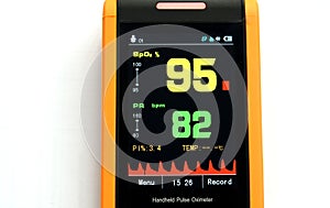 Display of the pulse oximeter showing blood oxygen ninety-five in yellow and pulse eighty-two in green.. photo
