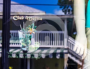 Display and reflection in Duval Street bar window with mannequin and saying Our Drinks Make You See Double But Feel Single - Key W