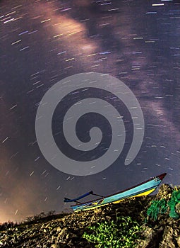Display of Star trails and Milky Way Galaxy appears above the boat