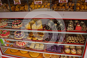 Display window of a bakery and pastry shop of with variety of baked goods, breads, donuts, puff pastry, closeup. Philippines.