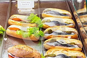 Display window show case of a bakery and pastry shop with assortment of healthy fast food sandwiches with salmon herring