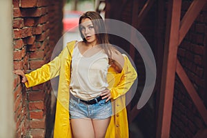 Displaying fashion tendencies. Dark-haired attractive woman posturing in bright yellow fluffy cloak.