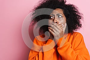 Displeased african american woman covering her mouth and looking aside