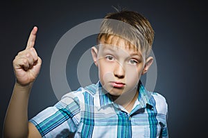 Displeased angry boy with threatens finger isolated on gray background