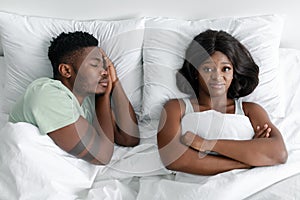 Displeased angry funny young african american lady suffering from snoring, sleeping man