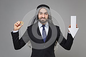 Displeased arabian muslim businessman in keffiyeh kafiya ring igal agal black suit isolated on gray background