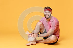 Displeased bearded fitness sporty guy sportsman in headband t-shirt in home gym isolated on yellow background. Workout