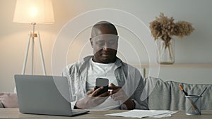 Displeased Black Man Using Smartphone Scrolling Negative News Sitting Indoors