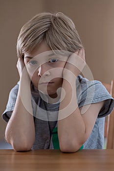 Displeased boy sitting at table