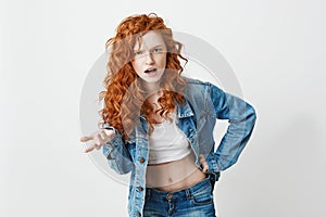 Displeased brutal redhead girl looking at camera not understanding over white background. Copy space.