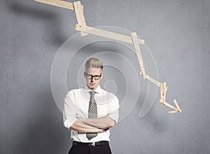 Displeased businessman in front of graph with negative trend.