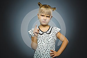 Displeased and contemptuous girl with threatens finger on gray background