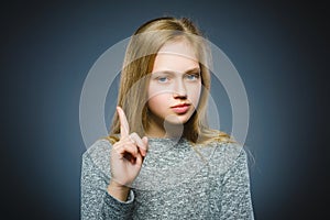 Displeased and contemptuous girl with threatens finger on gray background