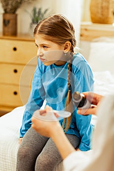 Displeased girl unwilling to take syrup suggested by a doctor