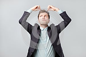 Displeased man in suit looking on his long hair ends.