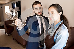 Displeased restaurateur showing dirty wineglass to waitress