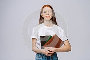 Displeased sad young woman college student holding book and crying on gray isolated background.