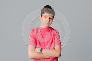 Displeased teenager boy feel offended, cross arms on chest, sulking and frowning bothered, standing upset on gray background