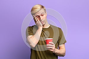 Displeased tired sleepy man with beverage in disposable plastic red cup