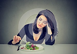 Displeased woman eating green leaf lettuce tired of diet restrictions