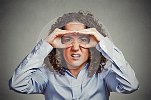 Displeased woman looking through fingers like binoculars photo