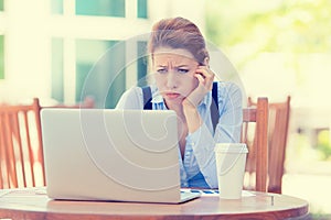 Displeased worried business woman sitting in front of laptop computer photo