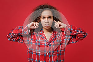 Displeased young african american girl in pajamas homewear posing resting at home isolated on red wall background. Relax
