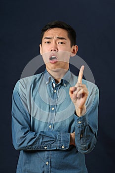 Displeased young Asian man gesturing with one hand