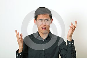 Displeased young Asian man gesturing with two hands photo