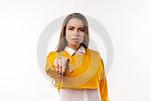 Displeased young brunette woman is pointing finger at camera, angry and furious with you. Studio shot, white background