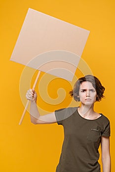 Displeased young protesting woman girl hold in hand protest sign broadsheet blank placard on stick isolated on yellow