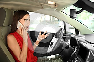 Displeased young woman talking by mobile phone on driver's seat of car