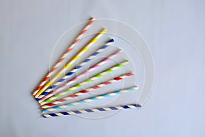 Disposable colorful striped paper cocktail sticks for party on blue background. Eco friendly paper drinking straws.