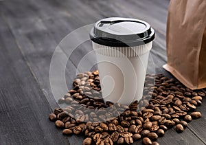 Disposable cup of coffee and coffee beans over dark wood background with space for your text