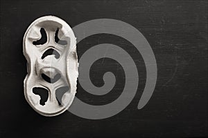 Disposable cup holder on a black wooden background.