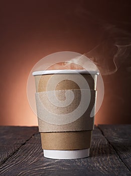Disposable Cup of steaming hot coffee on wooden table photo