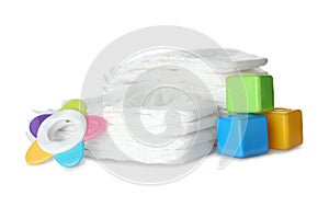 Disposable diapers, colorful cubes and teether on background