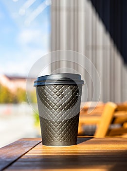 Disposable eco paper cup for hot drink with background of the city. Takeaway drink. Empty space for text, mockup