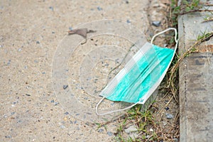 Disposable face mask on pavement dirty and causing the spread of pathogens