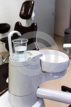 Disposable glass filled with CHX mouth rinse next to spiotoon bowl in dental clinic